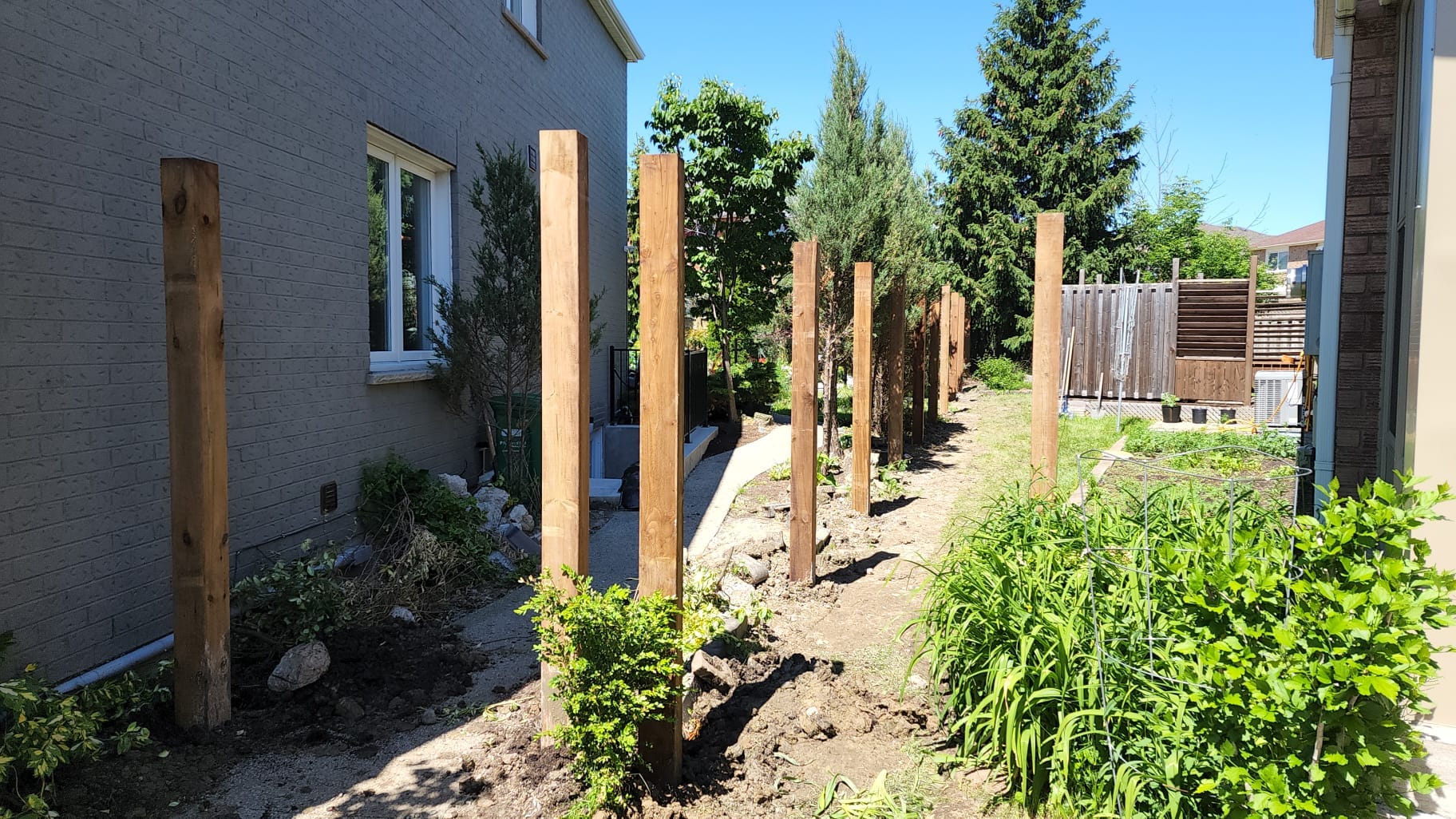 Wood fence posts set in gravel along backyard property line